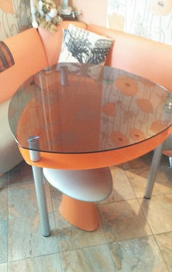 Стеклянный стол с подстольем на хромированных опорах в интерьере.