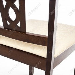 Деревянный стул с мягким сиденьем и резной спинкой. Обивка сиденья выполнена из бежевой ткани с рисунком. Цвет стула коричневый. Фрагмент стула