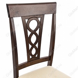 Деревянный стул с мягким сиденьем и резной спинкой. Обивка сиденья выполнена из бежевой ткани с рисунком. Цвет стула коричневый. Фрагмент стула